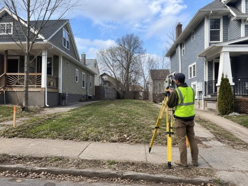 Lot Survey crew measuring a narrow infill housing parcel between existing homes in Knoxville Tennessee